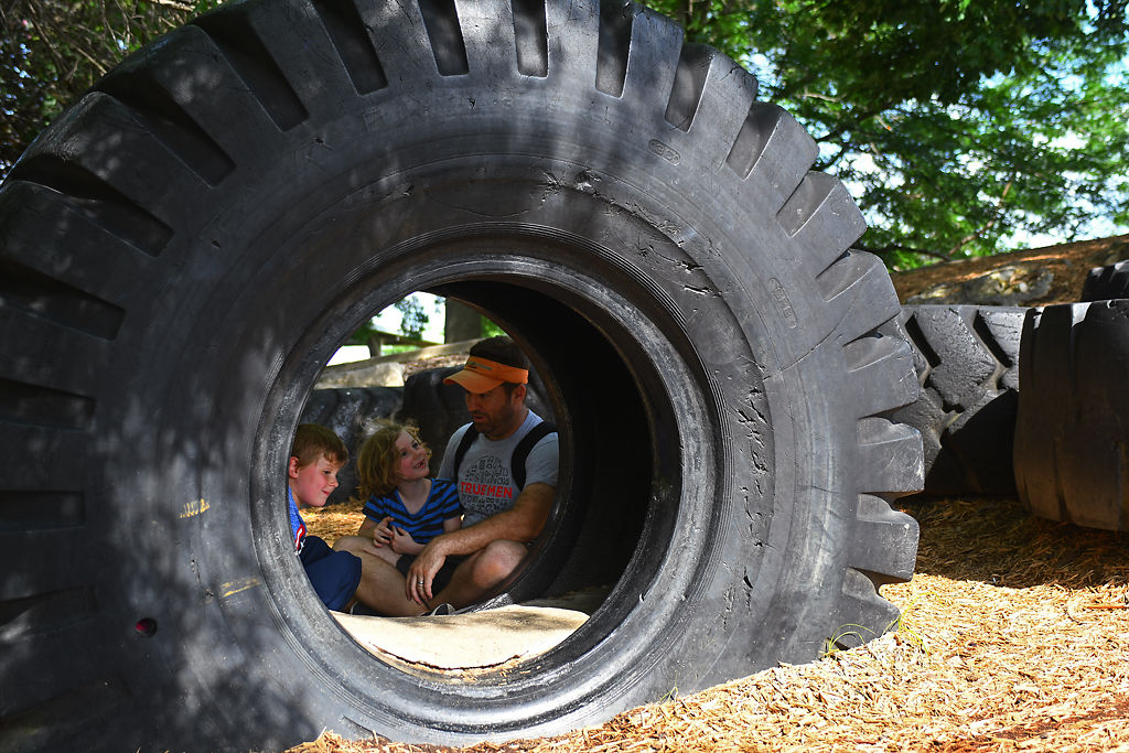 Corey Webble and his two kids Emma Grace, 6, and Harrison, 5, sit behind a giant tire